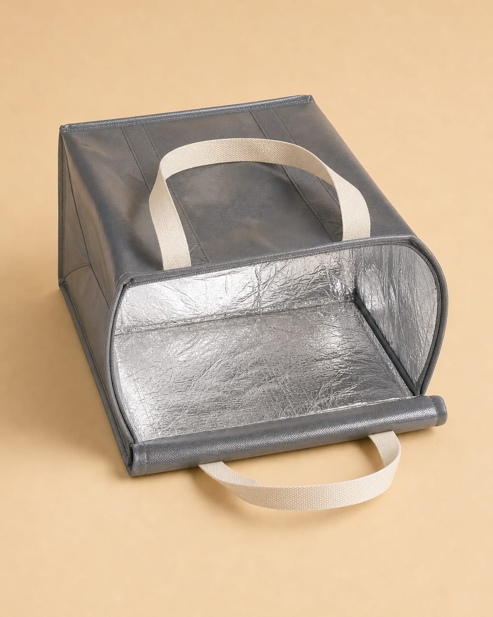 Charcoal insulated tote bag opened to show the aluminium foil lining, with cream webbing handles