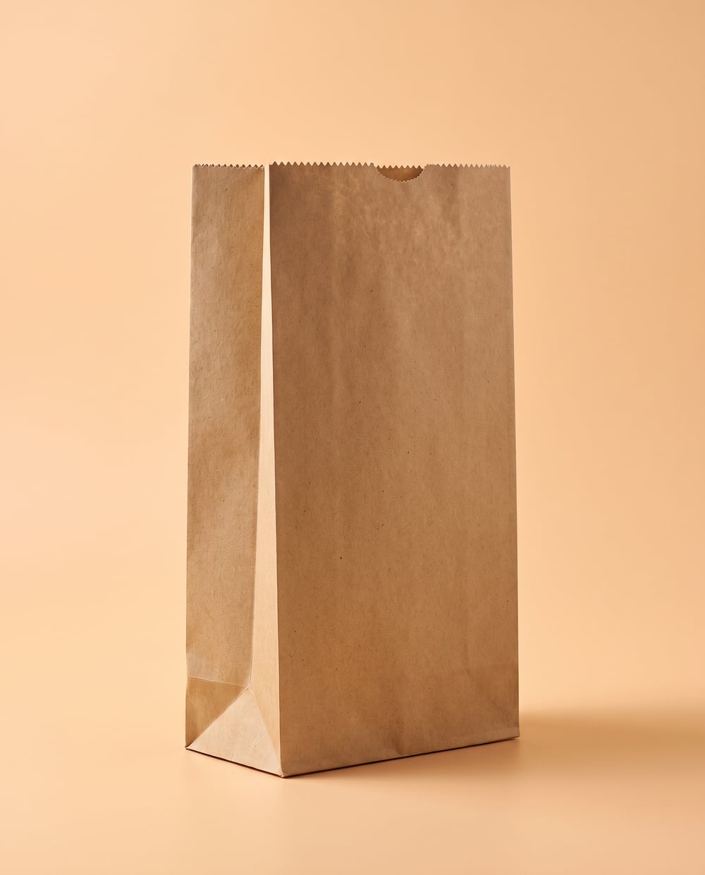Brown kraft SOS block bottom paper bag standing open, serrated top edge, no handles